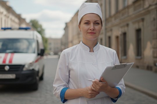Фельдшер на фоне машины скорой помощи