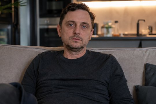 Мужчина сидит на диване, испытывая усталость, вызванную циррозом печени