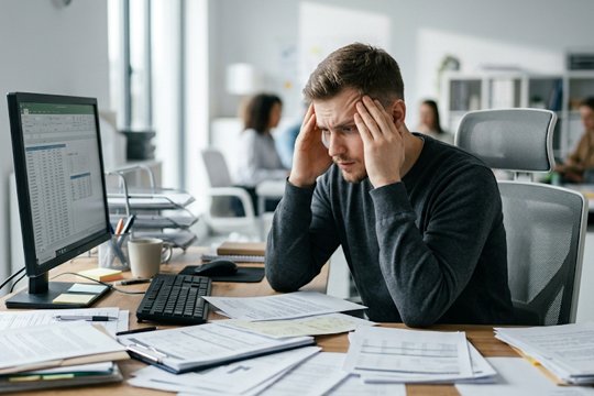 Мужчина, страдающий СДВГ, пребывает в растерянности, сидя за рабочим местом в офисе