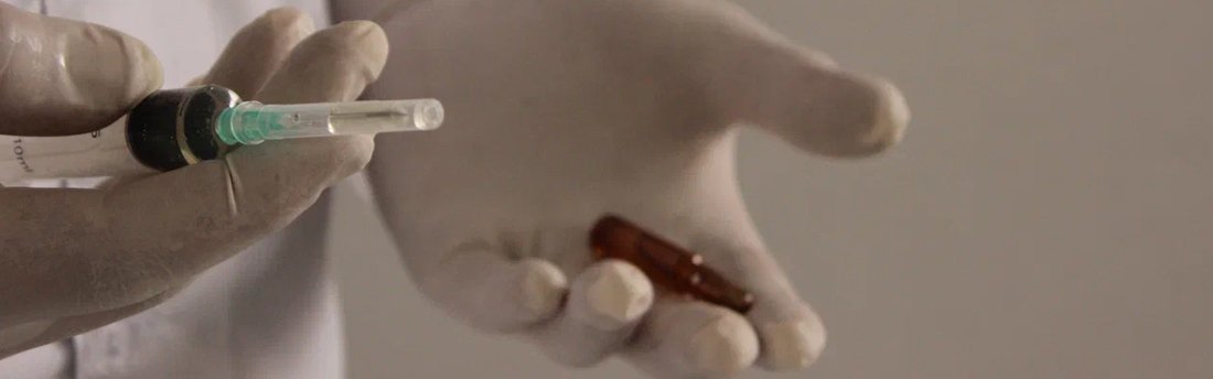 Врач держит в руках шприц и ампулу крупным планом