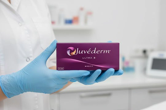 Врач держит в руках упаковку с гелем ювидерм для биоревитализации