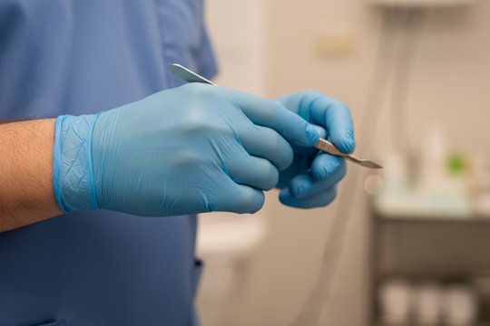 Врач держит в руке скальпель