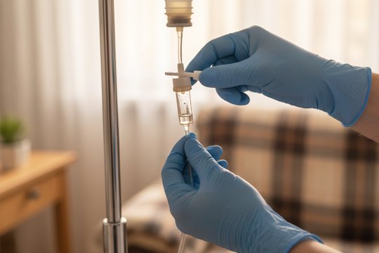 Врач настраивает капельницу при интоксикации на дому