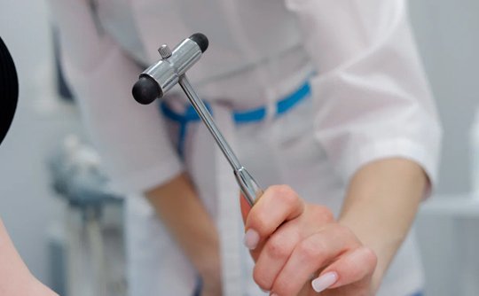 Врач простукивает руку пациента для реакции